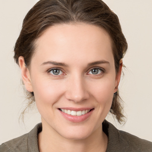 Joyful white young-adult female with medium  brown hair and grey eyes