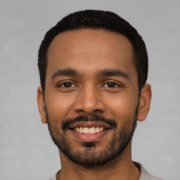 Joyful latino young-adult male with short  black hair and brown eyes