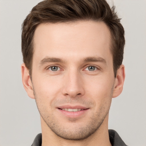 Joyful white young-adult male with short  brown hair and grey eyes