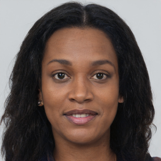 Joyful black young-adult female with long  brown hair and brown eyes