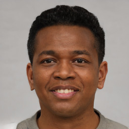 Joyful black young-adult male with short  brown hair and brown eyes
