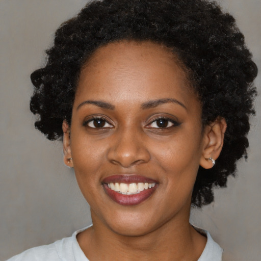 Joyful black young-adult female with short  black hair and brown eyes