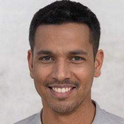 Joyful latino young-adult male with short  black hair and brown eyes