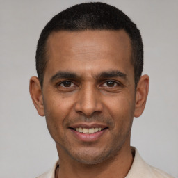 Joyful latino young-adult male with short  black hair and brown eyes