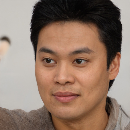 Joyful asian young-adult male with short  brown hair and brown eyes