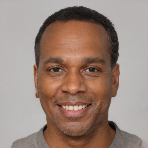 Joyful black adult male with short  black hair and brown eyes