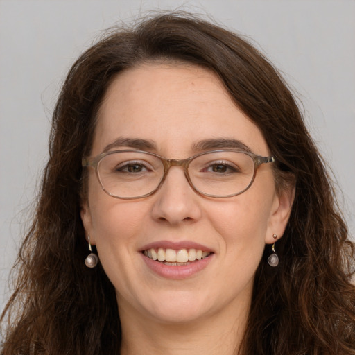 Joyful white adult female with long  brown hair and grey eyes