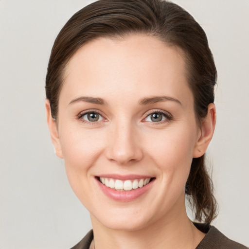 Joyful white young-adult female with medium  brown hair and grey eyes