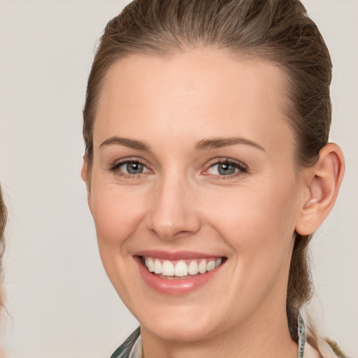 Joyful white young-adult female with medium  brown hair and grey eyes