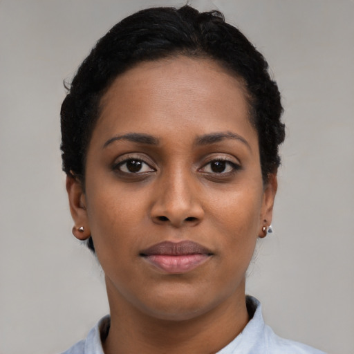 Joyful black young-adult female with short  brown hair and brown eyes