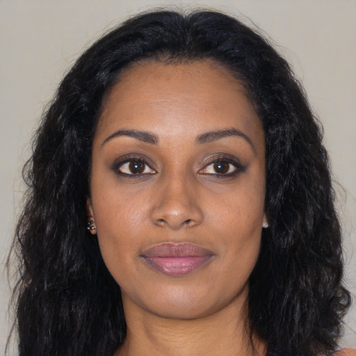 Joyful black young-adult female with long  black hair and brown eyes