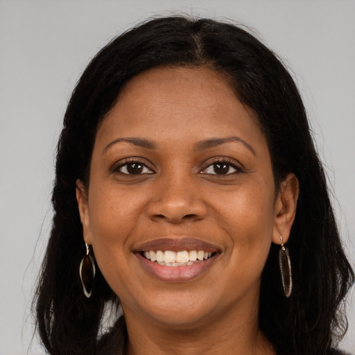 Joyful black young-adult female with long  brown hair and brown eyes