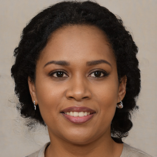 Joyful black young-adult female with long  brown hair and brown eyes
