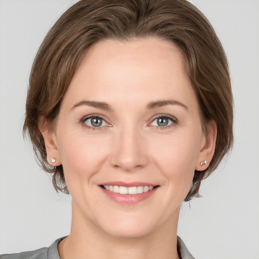 Joyful white young-adult female with medium  brown hair and grey eyes