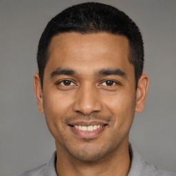 Joyful latino young-adult male with short  black hair and brown eyes