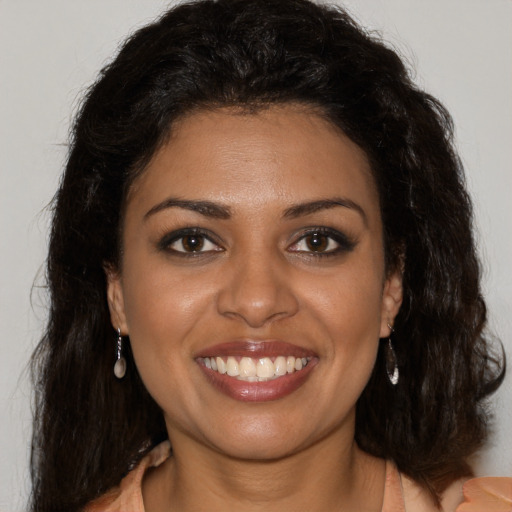 Joyful black young-adult female with long  brown hair and brown eyes