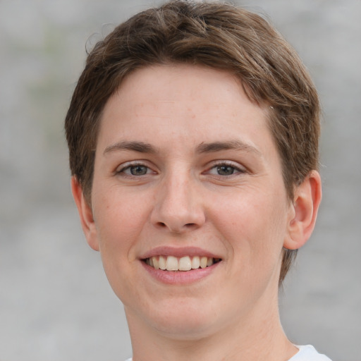 Joyful white young-adult female with short  brown hair and grey eyes