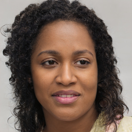 Joyful black young-adult female with long  brown hair and brown eyes