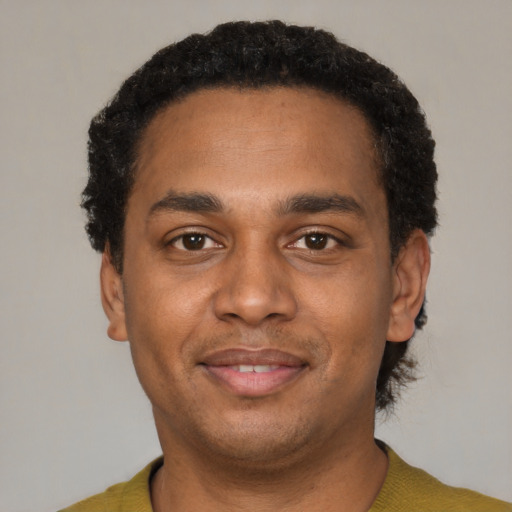 Joyful black young-adult male with short  black hair and brown eyes