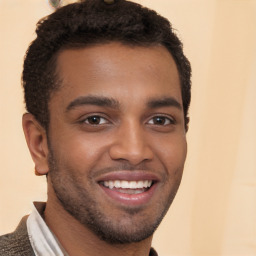 Joyful black young-adult male with short  brown hair and brown eyes