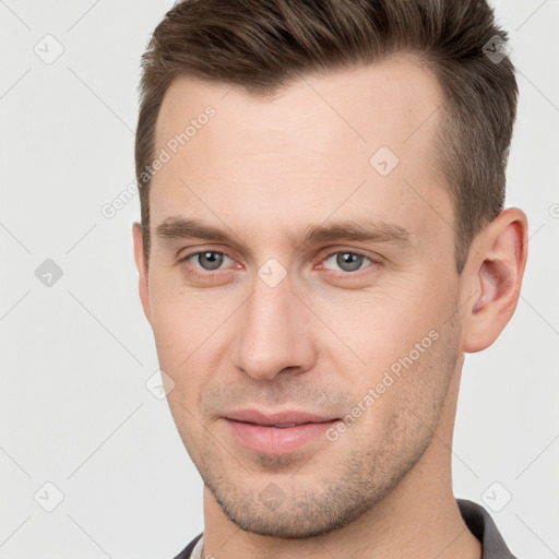 Joyful white young-adult male with short  brown hair and grey eyes