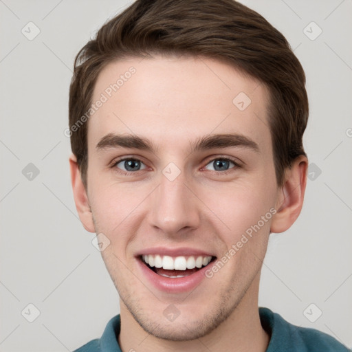 Joyful white young-adult male with short  brown hair and grey eyes