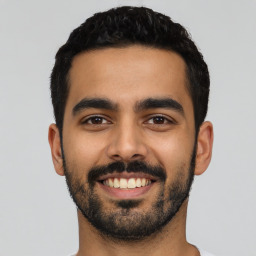 Joyful latino young-adult male with short  black hair and brown eyes