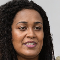 Joyful black young-adult female with long  brown hair and brown eyes