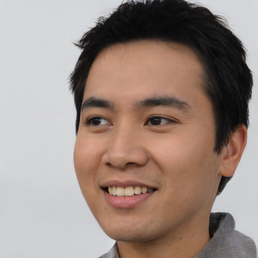 Joyful asian young-adult male with short  black hair and brown eyes