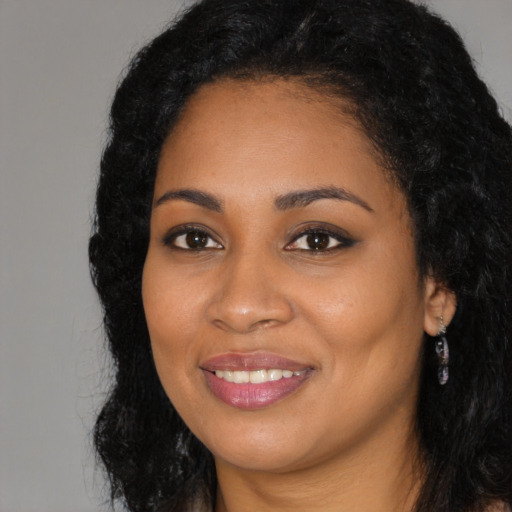 Joyful black young-adult female with long  black hair and brown eyes