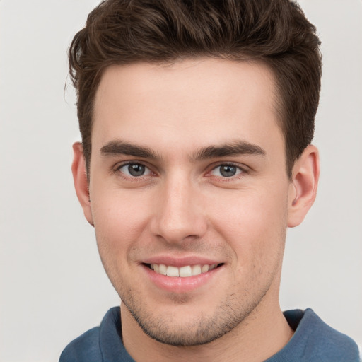 Joyful white young-adult male with short  brown hair and grey eyes