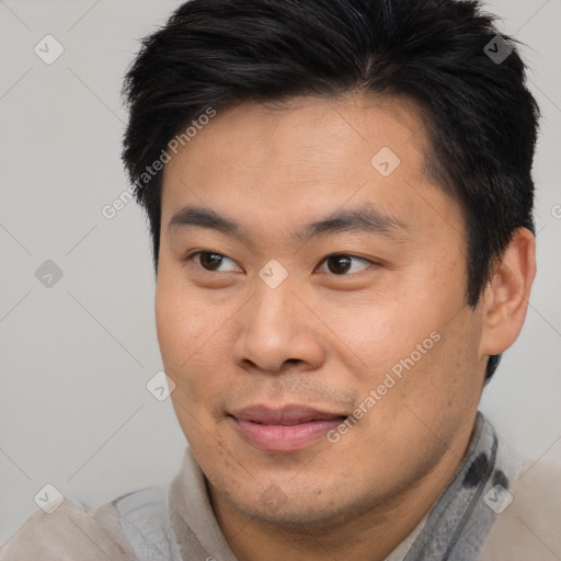 Joyful asian young-adult male with short  brown hair and brown eyes