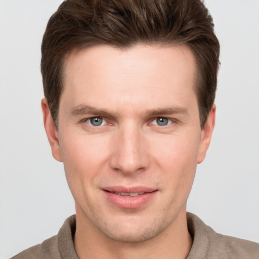 Joyful white young-adult male with short  brown hair and grey eyes