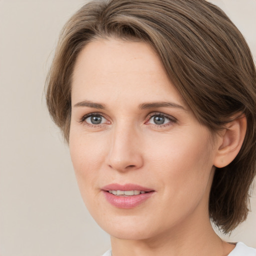 Joyful white young-adult female with medium  brown hair and grey eyes