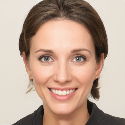 Joyful white young-adult female with medium  brown hair and grey eyes