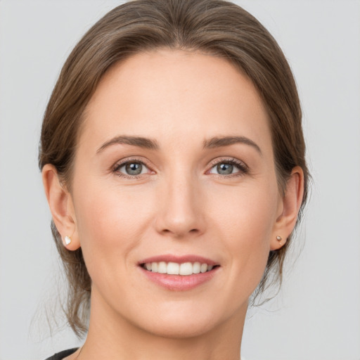 Joyful white young-adult female with medium  brown hair and grey eyes