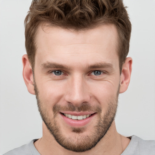 Joyful white young-adult male with short  brown hair and grey eyes