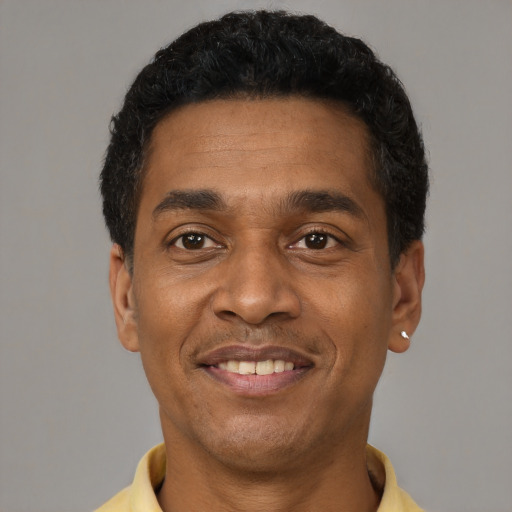Joyful black adult male with short  black hair and brown eyes