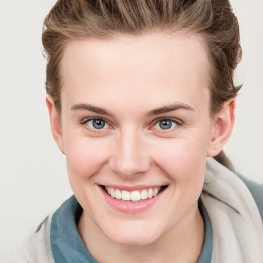 Joyful white young-adult female with short  brown hair and blue eyes