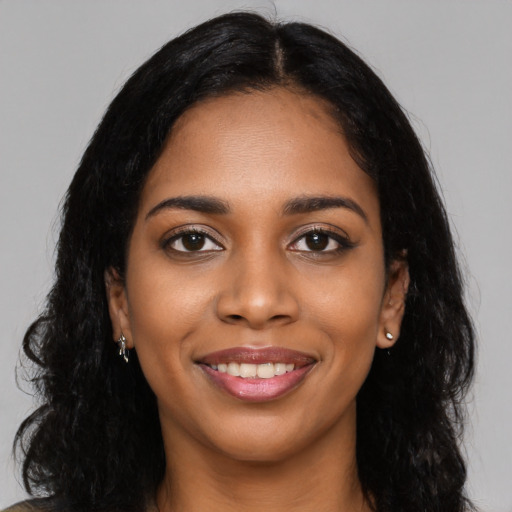Joyful black young-adult female with long  black hair and brown eyes