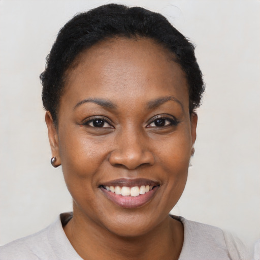 Joyful black young-adult female with short  black hair and brown eyes