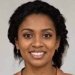 Joyful black young-adult female with long  brown hair and brown eyes