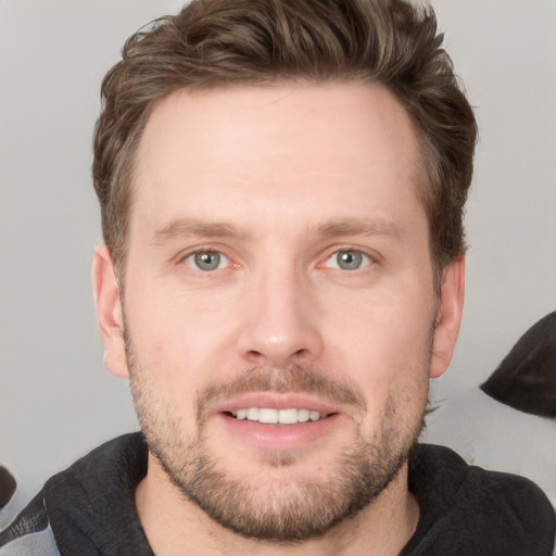 Joyful white young-adult male with short  brown hair and grey eyes