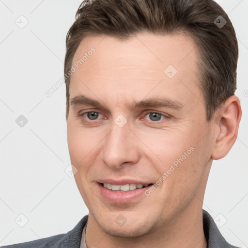 Joyful white young-adult male with short  brown hair and grey eyes