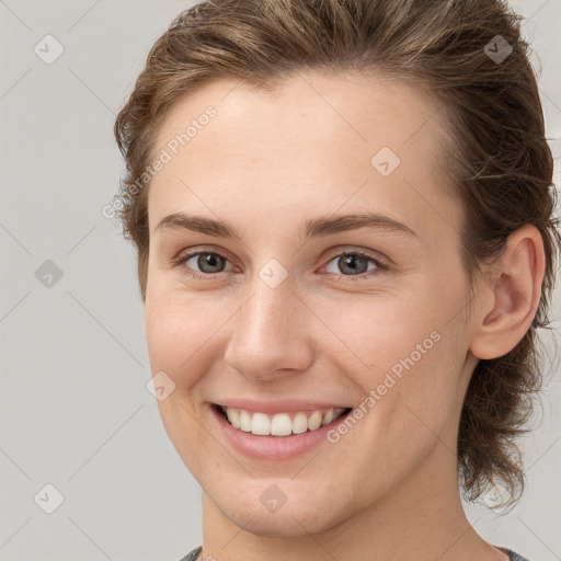 Joyful white young-adult female with medium  brown hair and grey eyes