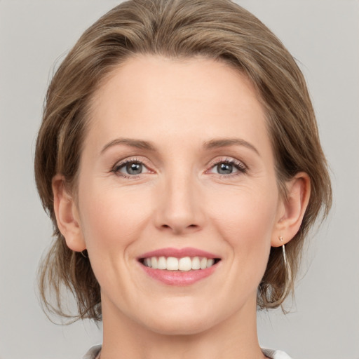 Joyful white young-adult female with medium  brown hair and grey eyes