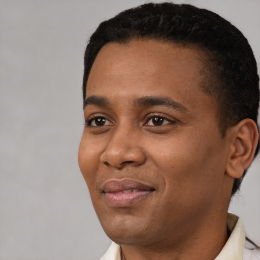 Joyful black young-adult male with short  black hair and brown eyes