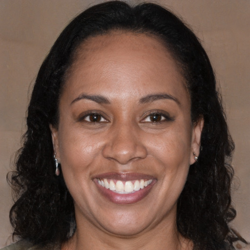 Joyful black adult female with long  brown hair and brown eyes