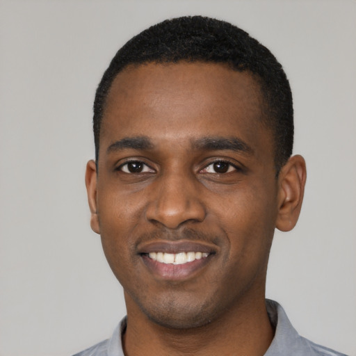Joyful black young-adult male with short  black hair and brown eyes