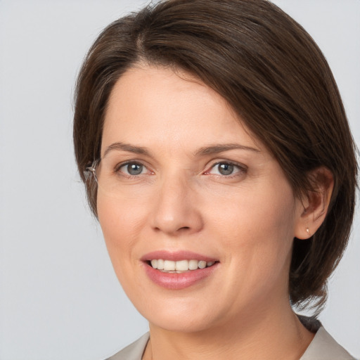 Joyful white young-adult female with medium  brown hair and grey eyes